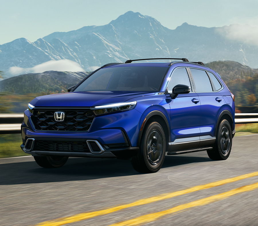 Front 3/4 shot of Blue 2023 Honda CR-V driving down road overlooking mountains.