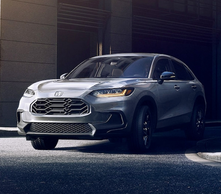 Front driver-side view of the 2023 Honda HR-V Sport in Urban Gray Pearl shown driving in an urban area.