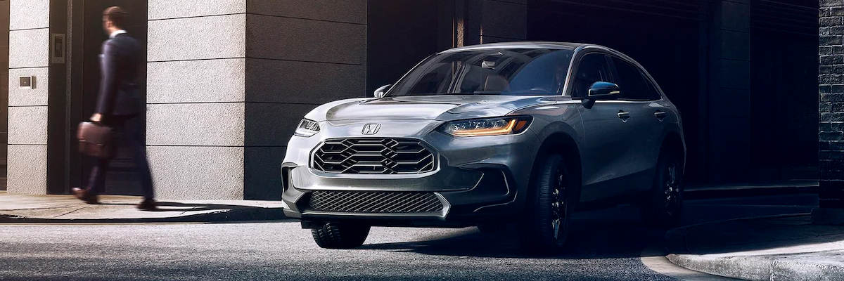 Front driver-side view of the 2023 Honda HR-V Sport in Urban Gray Pearl shown turning onto a city street.