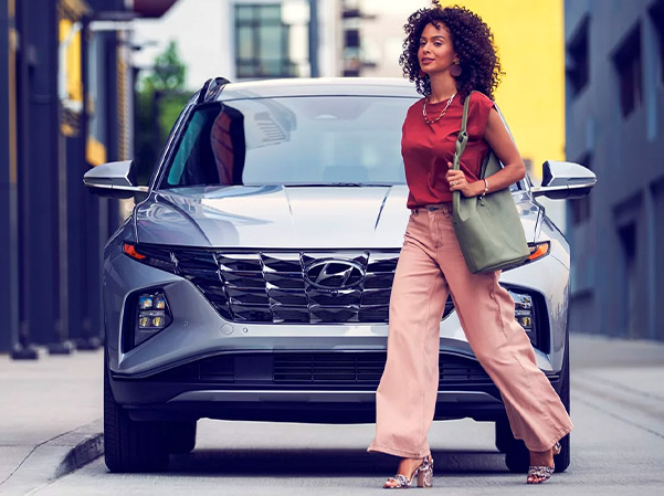 Front view of 2023 Hyundai Tucson with woman walking past it