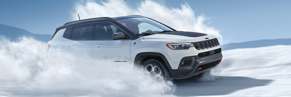 2022 Compass Trailhawk in Bright White driving through snow.