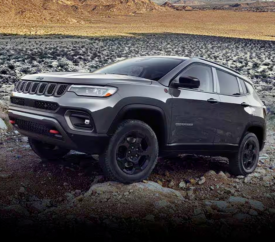 A 2023 Jeep Compass Trailhawk crawling over large and small rocks and stones off-road.