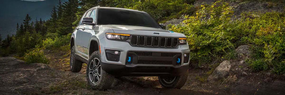 The 2023 Jeep Grand Cherokee 4XE rounding a curve on a mountain road.