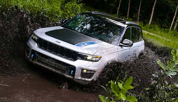 The 2023 Jeep Grand Cherokee 4XE driving through a muddy puddle