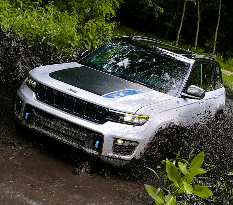 The 2023 Jeep Grand Cherokee being driven through muddy water.