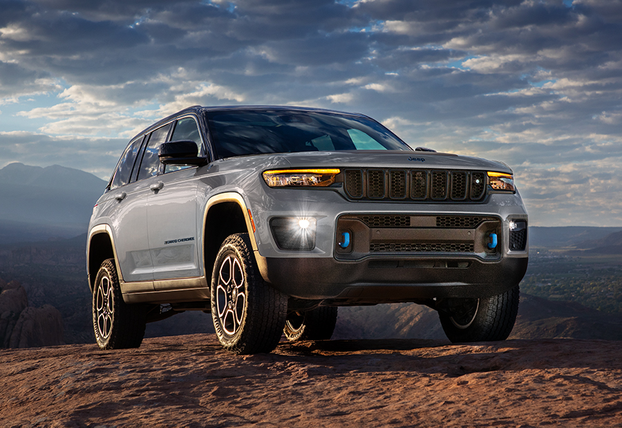 2023 Grand Cherokee Trailhawk 4xe in Silver Zynith parked atop a rock surface with a mountainous valley visible in the distance