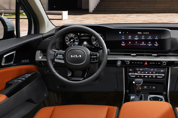 Interior shot of a 2023 Kia Carnival steering wheel and dashboard.