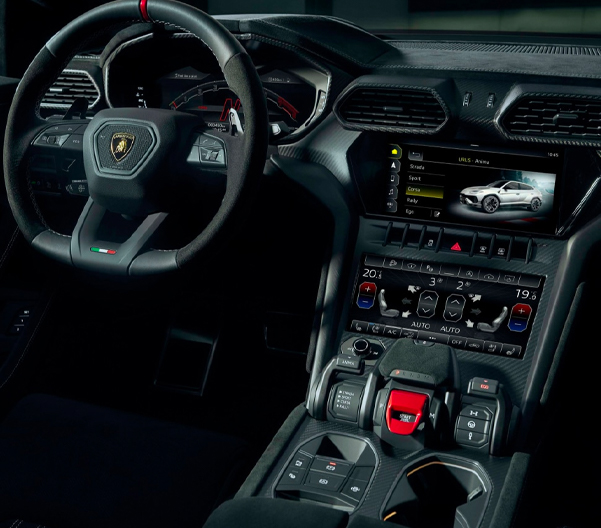 An interior shot of a New Lamborghini Urus S touchscreen and steering wheel.