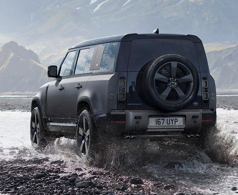 Rear shot of a 2023 Land Rover Defender with mountains in the background.