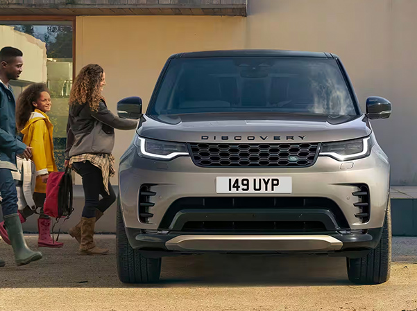 2023 Land Rover Discovery parked in front of house with family getting in.