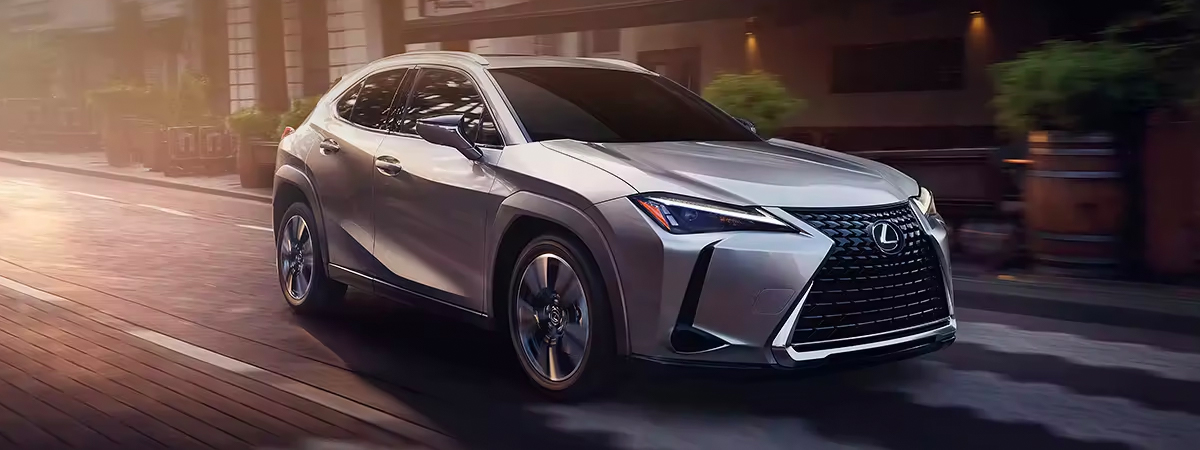 Front 3/4 shot of 2024 Lexus UX driving through the city streets.