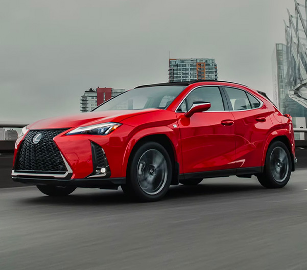 Front 1/4 shot of red 2023 Lexus UX driving on bridge.