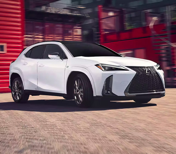 Front 3/4 shot of white 2023 Lexus UX turning onto dirt road.