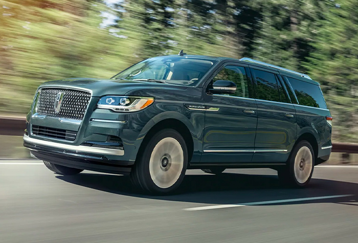 A 2023 Lincoln Navigator® SUV is being driven along a road