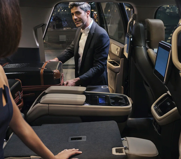 A man is pulling a suitcase out of the folded-flat second row of a 2023 Lincoln Black Label Navigator® SUV.