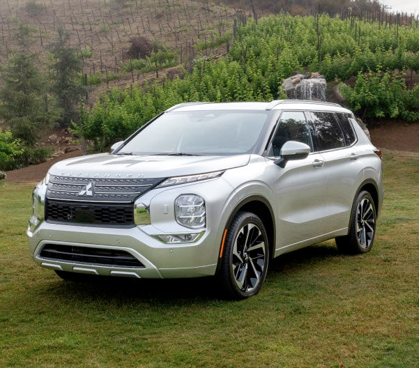 Angled view of a silver 2023 Mitsubishi Outlander SUV parked in a green field