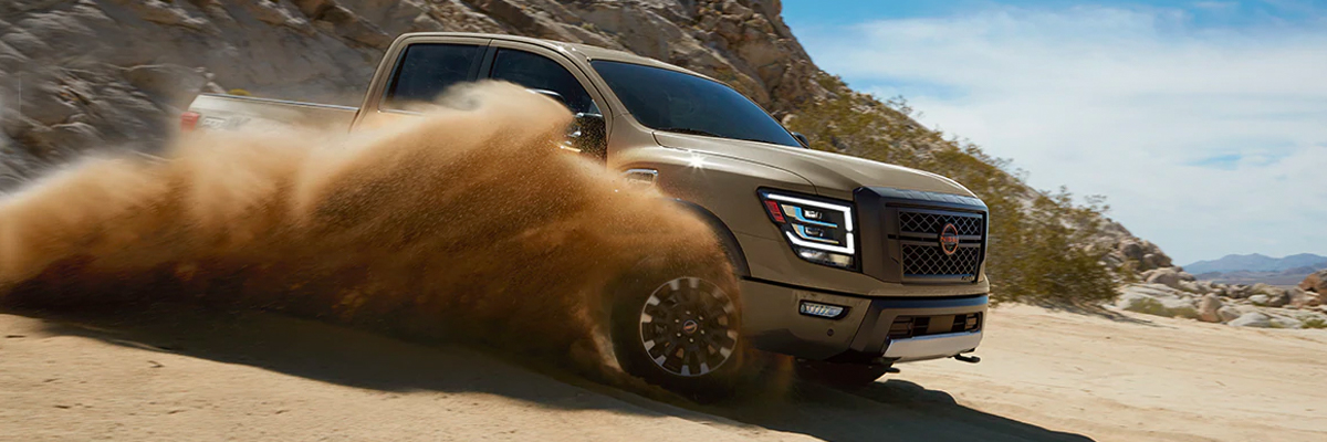 2023 Nissan TITAN PRO-4X off road kicking up sand.