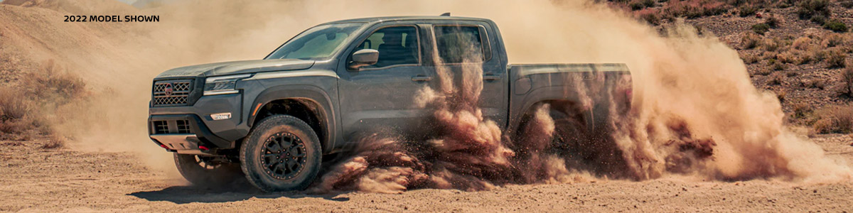 The 2022 Nissan Frontier driving around in dirt, kicking up dust