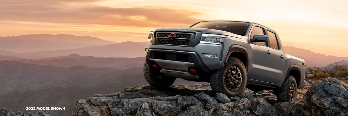 The 2022 Nissan Frontier parked on a rocky ledge with a sunset in the background