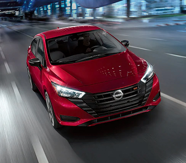 2023 Nissan Versa at night showing updated front fascia and signature LED headlights.