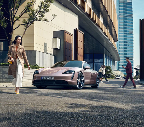 2023 Porsche Taycan parked outside of a modern building with people walking around