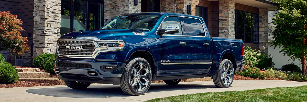 The 2023 Ram 1500 parked in the driveway of a large house.