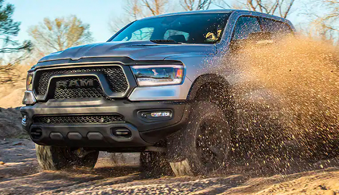 The 2023 Ram 1500 Rebel being driven off-road with dirt spraying up from its wheels.