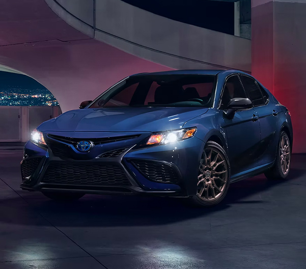 Front 3/4 shot of 2023 Toyota Camry Hybrid in parking garage at night.