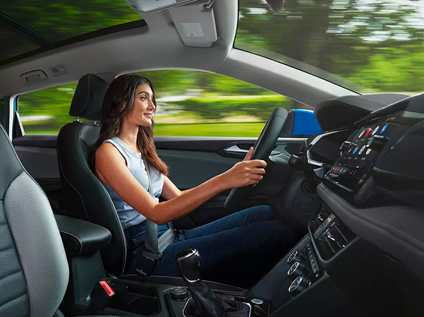 Woman driving in 2023 VW Taos smiling.