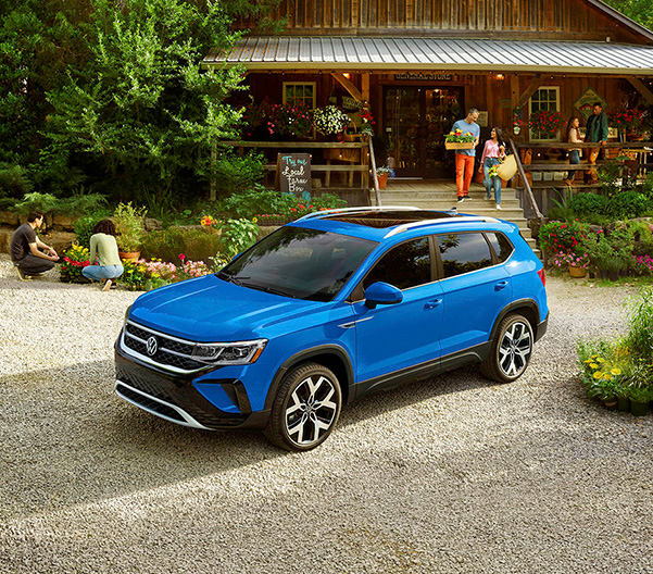 A Taos shown in Cornflower Blue is parked at a countryside market.