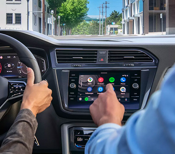 Passenger selecting app from dash infotainment touchscreen display with left index finger.