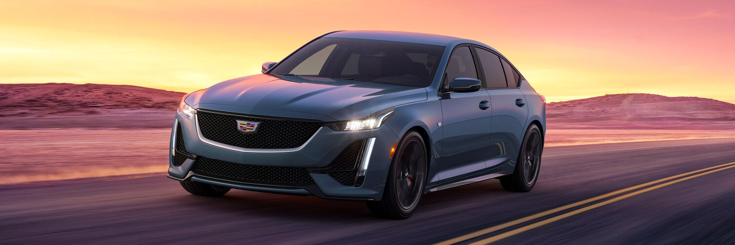 Front 3/4 shot of the 2024 Cadillac CT5 driving down road at sunset