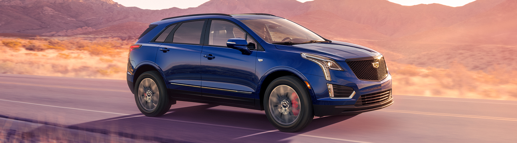 2024 Cadillac XT5 Sport Platinum 7/8 passengers side front view of vehicle on road with mountains in background