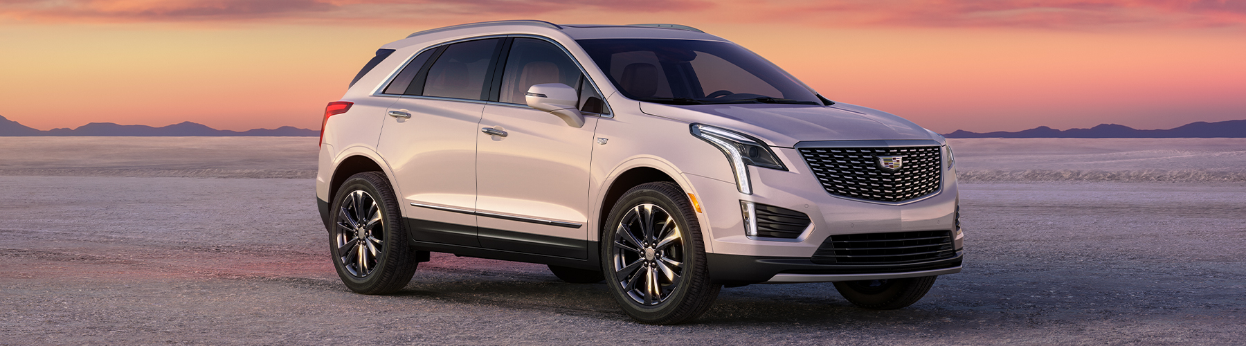 2024 Cadillac XT5 Premium Luxury 3/4 passenger side front view of vehicle on road with pink clouds