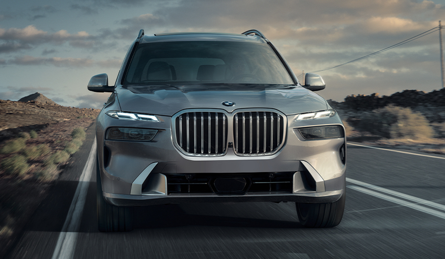 Front view of the 2024 BMW X7 driving down a highway at dusk