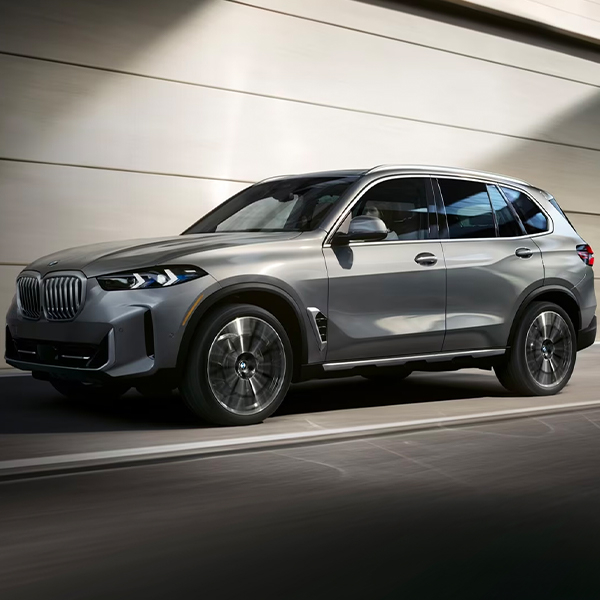 Exterior shot of a 2024 BMW X5 driving on a city street.
