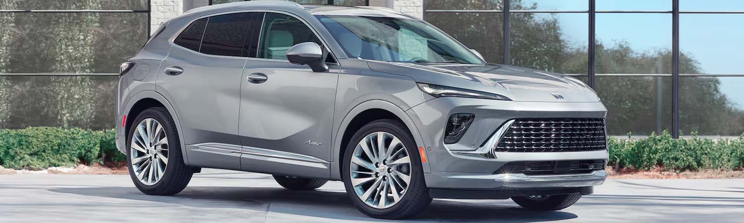 3/4 shot of a 2024 Buick Envision parked in front of a modern building with a garden bed full of bushes