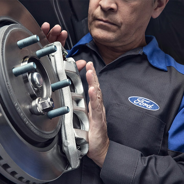 Ford Dealer Technician checking brakes on a vehicle at a dealership