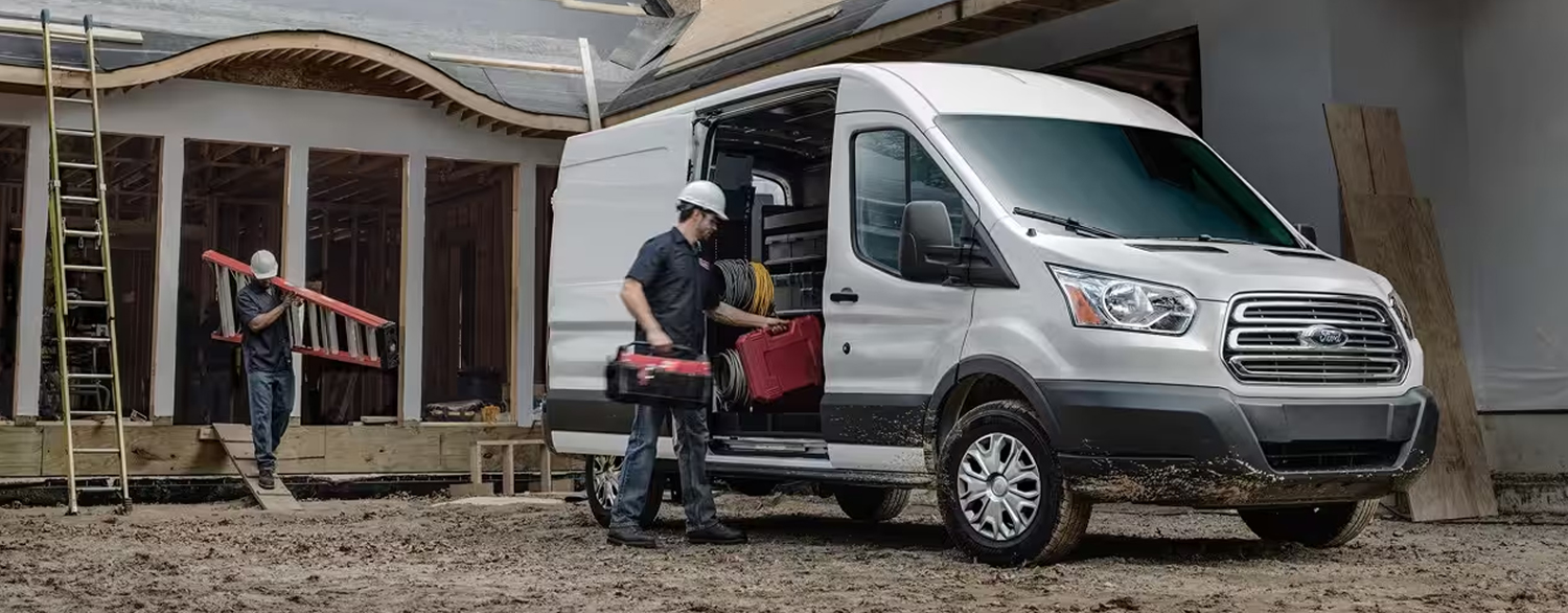View of a worker loading equipment into a parked Ford Transit Cargo Van