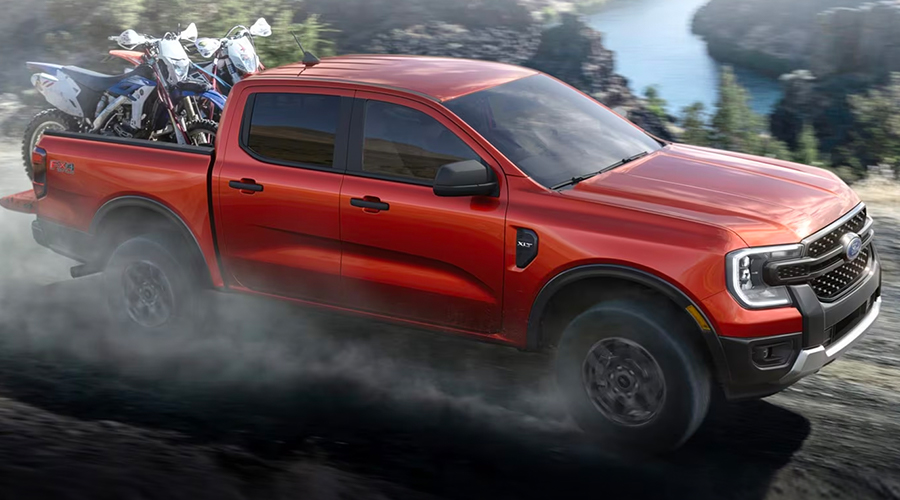 A 2024 Ford Ranger® in Hot Pepper Red with an extra cost option with dirt bikes being hauled and driven off-road.