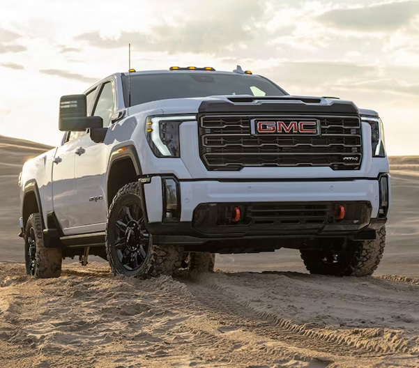 The All White New GMC Sierra HD Driving Off-Road Up a Sand Dune