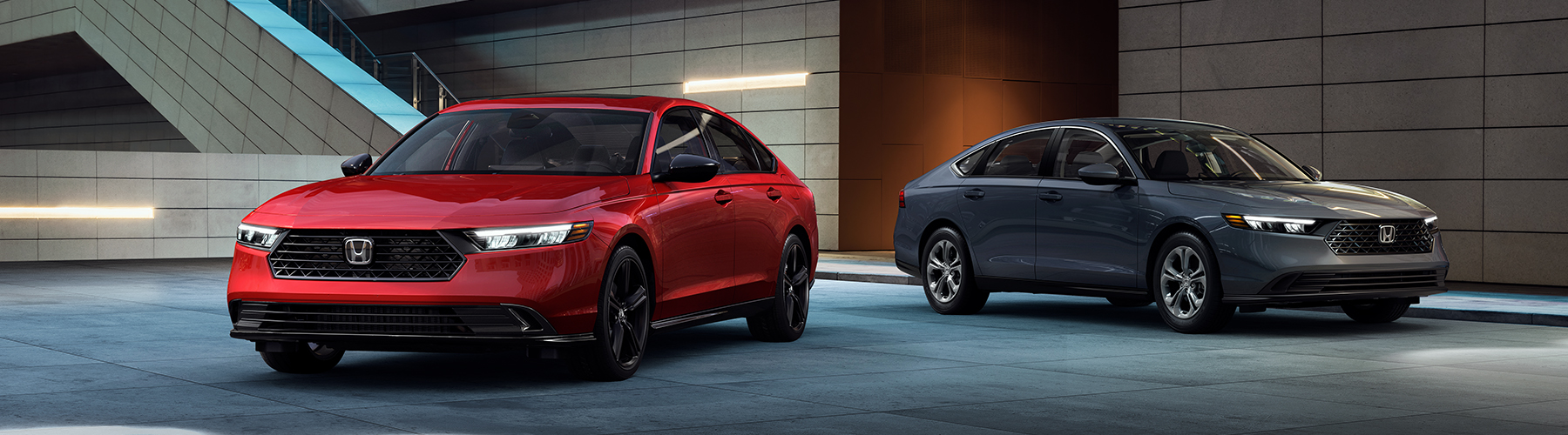 Two 2024 Accord Hybrid vehicles parked in front of a modern building.