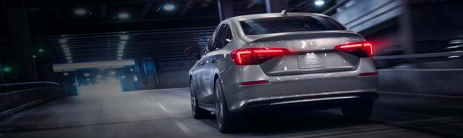 Rear of 2024 Honda Civic driving down city road at night