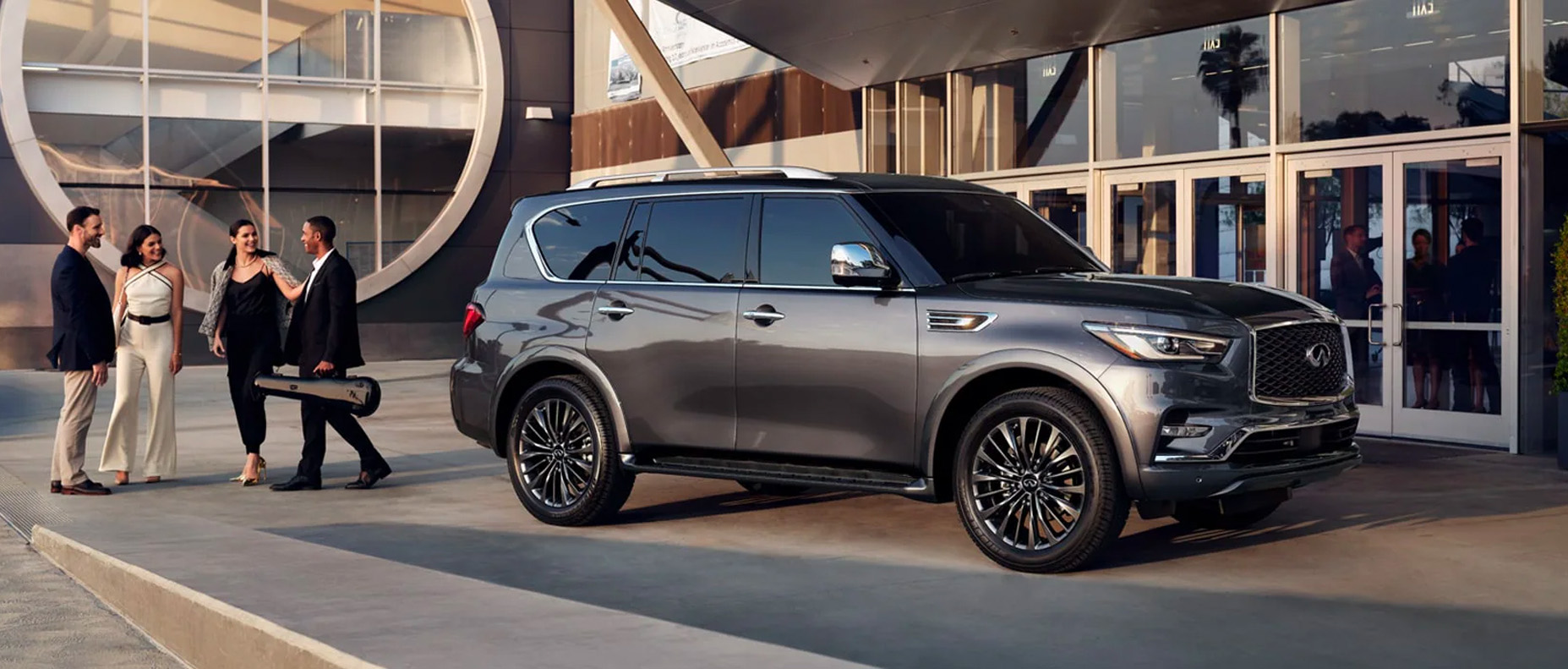 Front profile of 2024 INFINITI QX80 exterior parked with a party of people