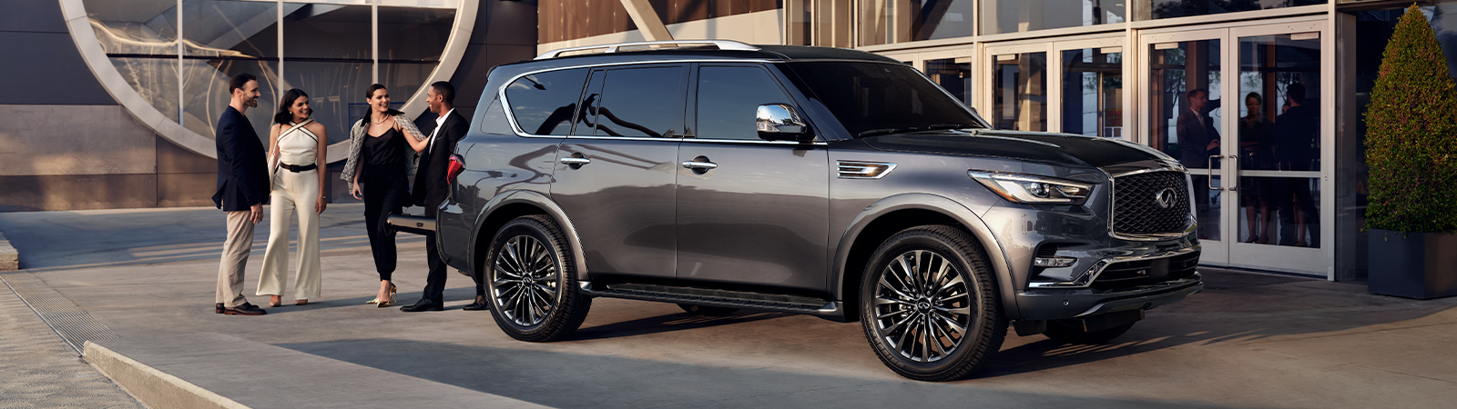 Front 7/8 view of 2024 INFINITI QX80 SUV parked by people