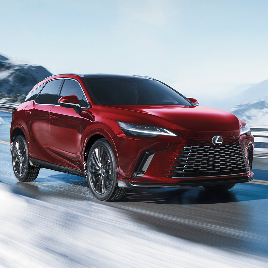 Exterior shot of the 2024 RX Hybrid shown in Nightfall Mica driving along a snowy road. 