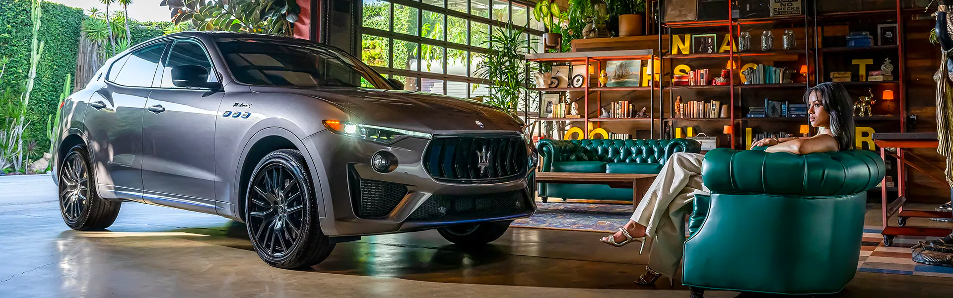Maserati Levante parked in a garage next to a person on a couch.
