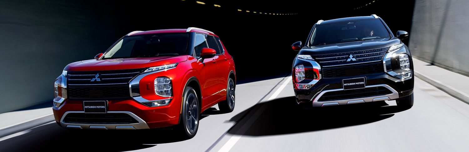 A red and black 2024 Mitsubishi Outlander SUV driving side by side