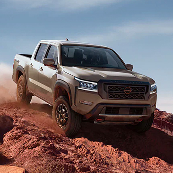 Front 3/4 shot of the 2024 Nissan Frontier driving down clay cliffside