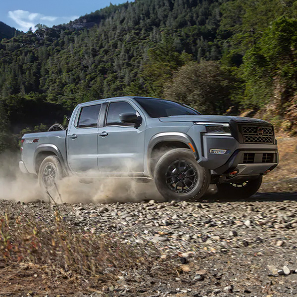 Side profile shot of 2024 Nissan Frontier kicking up dirt offroad